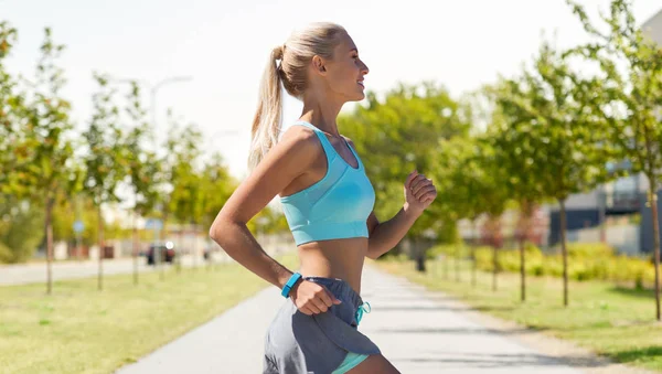 Smiling young woman running outdoors — Stock Photo, Image