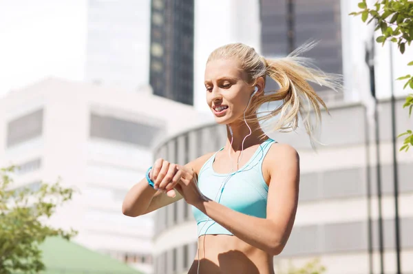 Mujer feliz con rastreador de fitness y auriculares — Foto de Stock