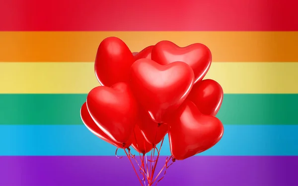 Gökkuşağı bayrağı üzerinde kırmızı kalp şeklinde helyum balonları — Stok fotoğraf