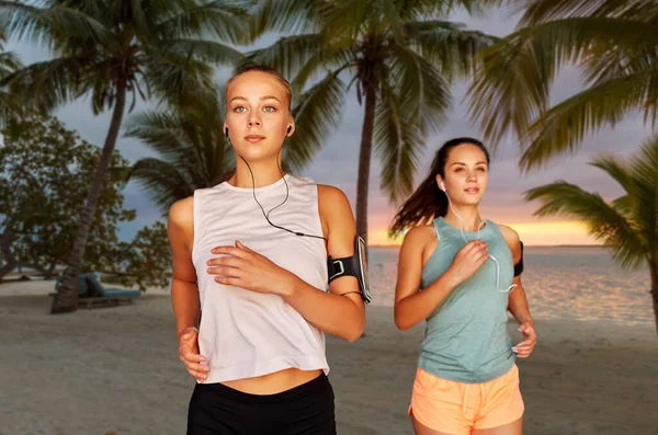 young women with earphones and smartphones running