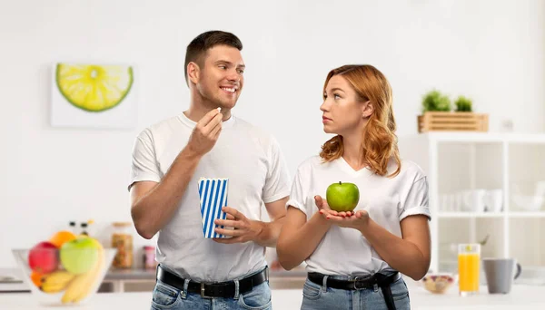Pár v bílých tričkách s popcornem a jablkem — Stock fotografie