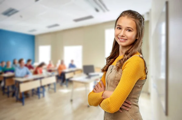 Fille étudiante souriante avec les bras croisés à l'école — Photo