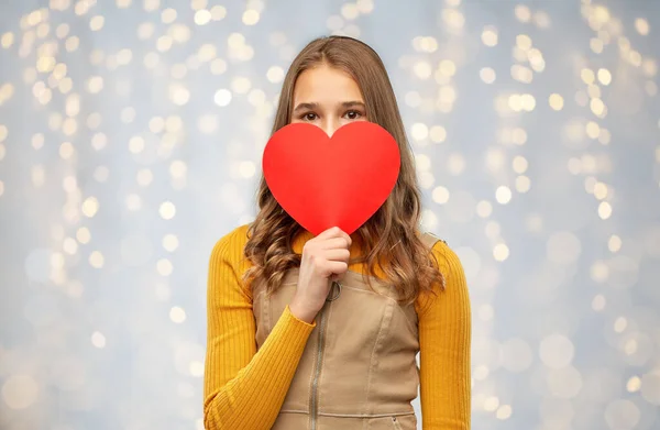 Glimlachend tiener meisje verbergen over rood hart — Stockfoto