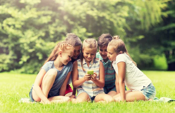 Crianças ou amigos com smartphone no parque de verão — Fotografia de Stock