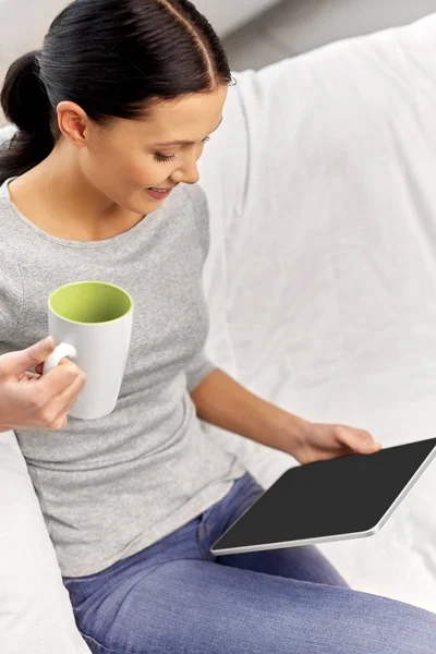 Young woman with tablet computer and mug at home — Stock Photo, Image
