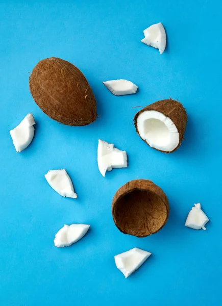 Whole and cracked coconut on blue background — 스톡 사진