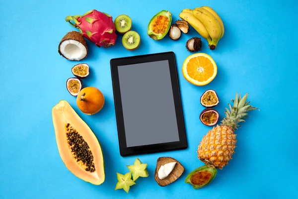 Frutas em torno do computador tablet no fundo azul — Fotografia de Stock