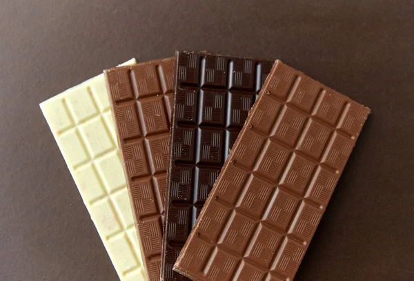 Diferentes tipos de chocolate no fundo marrom — Fotografia de Stock