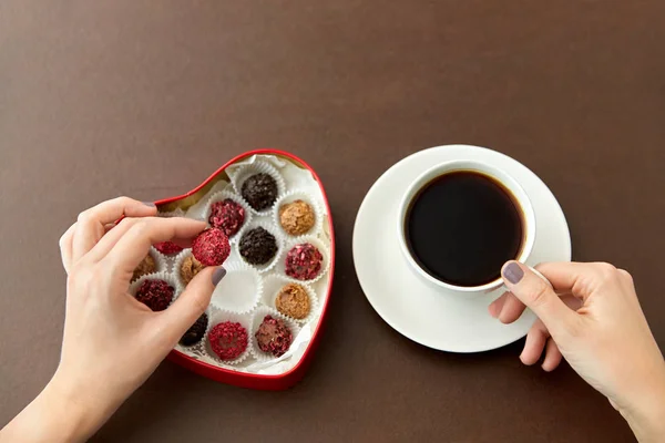 Mani, caramelle in scatola a forma di cuore e tazza di caffè — Foto Stock