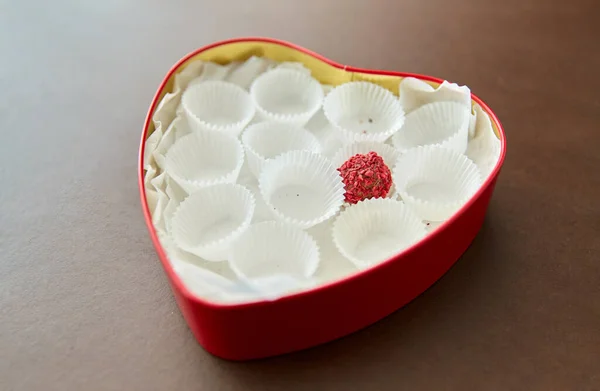 Одна цукерка в шоколадній коробці у формі червоного серця — стокове фото