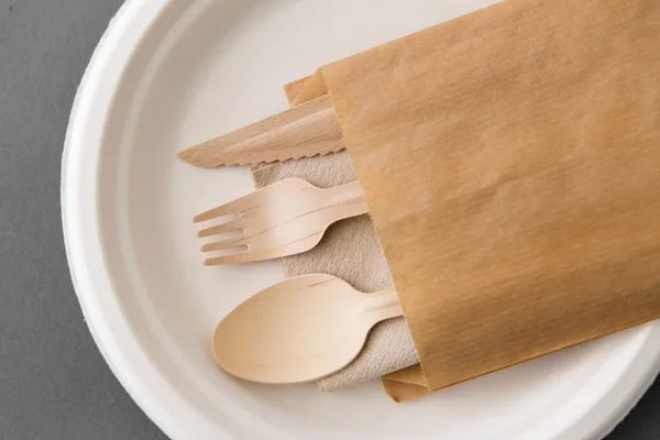 Wooden spoon, fork and knife on paper plate — Stock Photo, Image