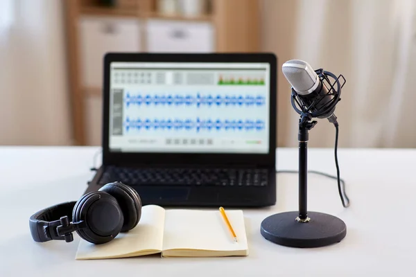 Mikrofon, bärbar dator, hörlurar, anteckningsbok på bordet — Stockfoto