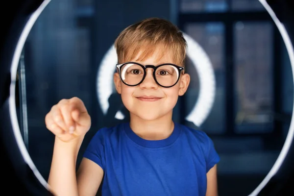 Chlapec v brýlích nad osvětlením v tmavé místnosti — Stock fotografie