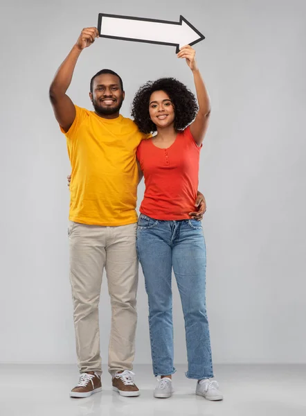 Happy african american couple holding arrow — Stock Photo, Image
