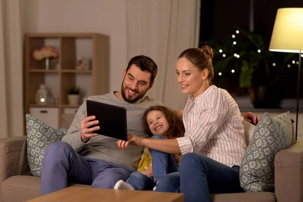 Happy family with tablet computer at home at night — 스톡 사진