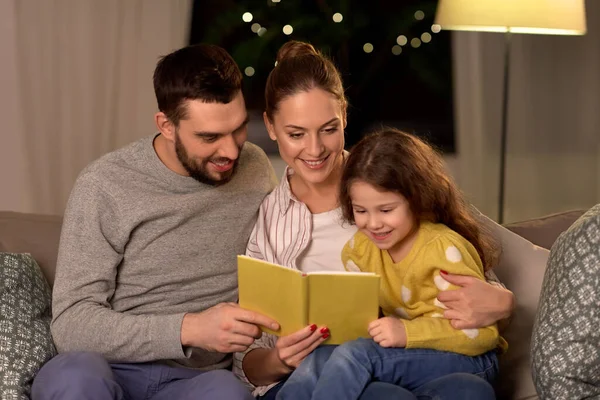 Lycklig familj läsa bok hemma på natten — Stockfoto
