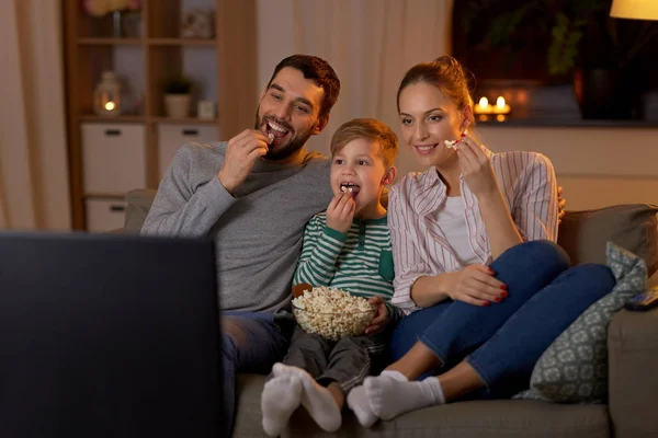 Familia feliz con palomitas de maíz viendo la televisión en casa —  Fotos de Stock