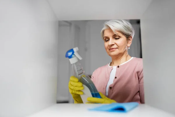 Starsza kobieta sprzątanie stojak z detergentem w domu — Zdjęcie stockowe