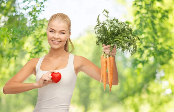 Glücklich lächelnde junge Frau mit Herz und Karotten — Stockfoto