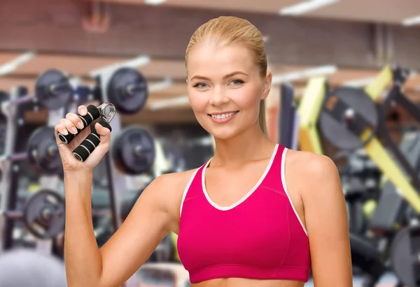Mujer sonriente con expansor de manos haciendo ejercicio en el gimnasio —  Fotos de Stock
