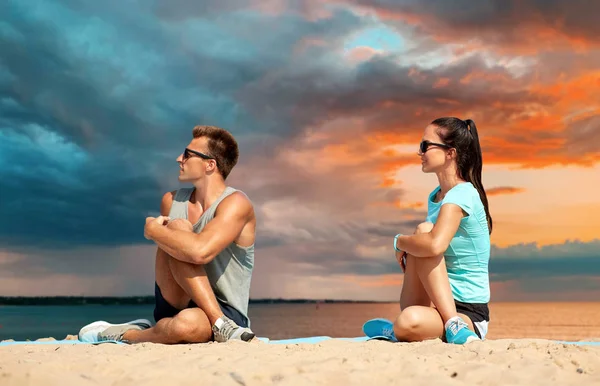 Smiling couple stretching legs on beach — Stock Photo, Image