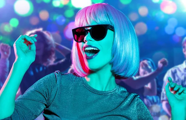 Женщина в парике и солнечных очках танцует в ночном клубе — стоковое фото