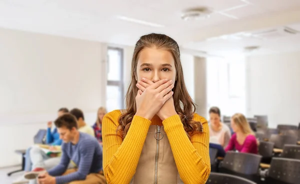 Scared student girl closing mouth at school — Stockfoto