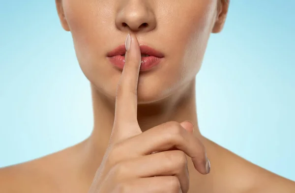 Beautiful young woman holding finger on lips — Stock Photo, Image