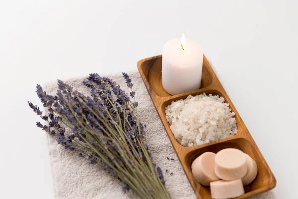 Havssalt, tvål, ljus och lavendel på badhandduk — Stockfoto