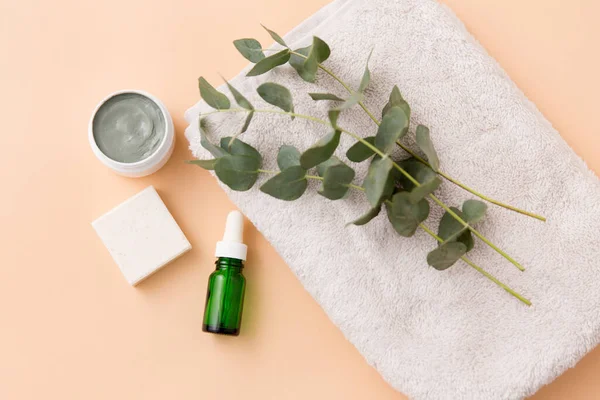 Serum, clay mask, oil and eucalyptus on bath towel — Stock Photo, Image