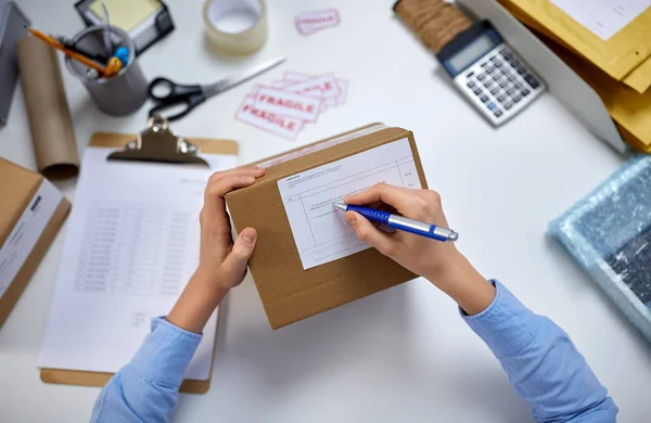 Close up of hands filling form on parcel at office — Stok fotoğraf