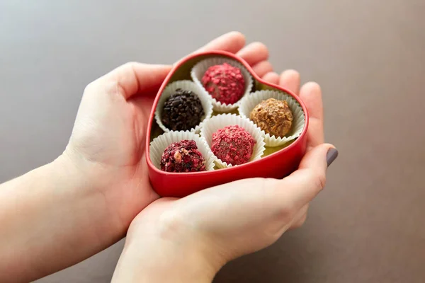 Manos con caramelos en forma de corazón caja de chocolate —  Fotos de Stock