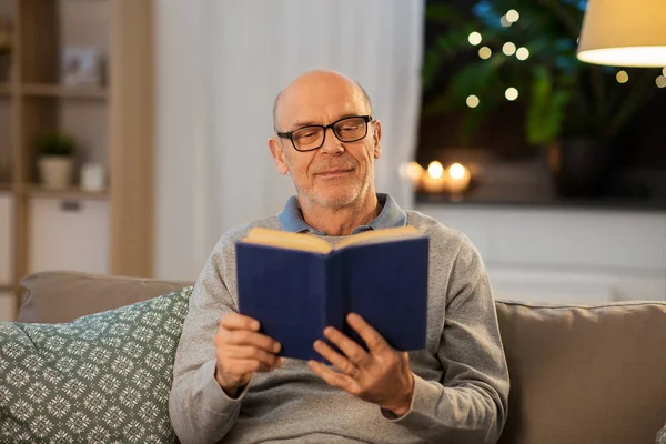 Heureux chauve senior homme sur canapé lecture livre à la maison — Photo