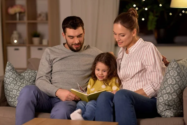 Lycklig familj läsa bok hemma på natten — Stockfoto