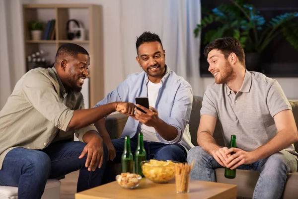 Amigos do sexo masculino com smartphone beber cerveja em casa — Fotografia de Stock