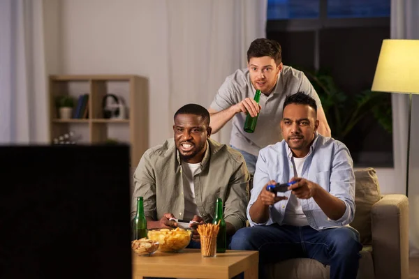 Amigos felices jugando videojuegos en casa por la noche — Foto de Stock