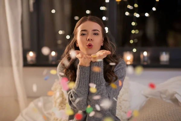 woman blowing confetti from her hands at home