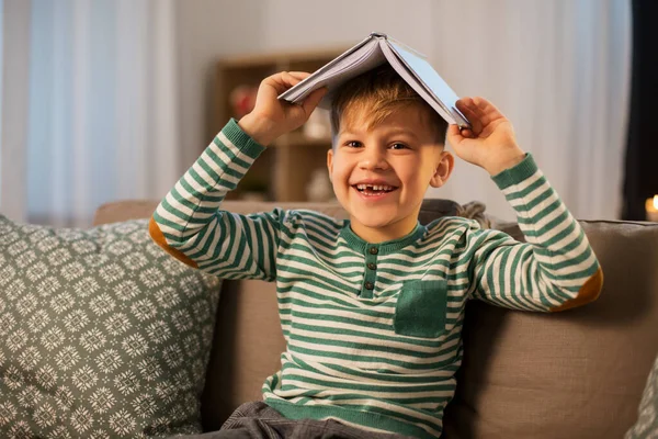 Счастливый мальчик с книгой весело провести время дома — стоковое фото