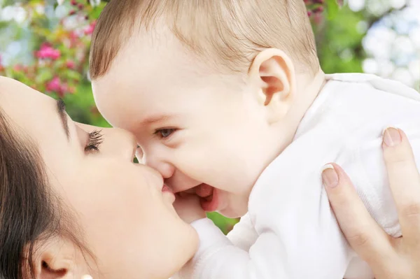 Primer plano de la madre besando bebé sobre el jardín —  Fotos de Stock