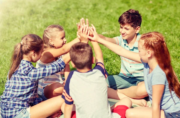 Grupo de niños felices haciendo alta cinco al aire libre — Foto de Stock