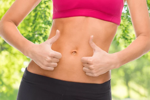 Close up of woman showing tummy and thumbs up — Stock Photo, Image