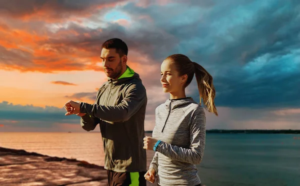 Koppel met fitness trackers lopen over zee — Stockfoto