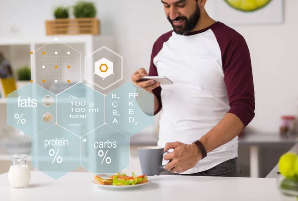 Homme avec téléphone et nourriture tableau de la valeur nutritive — Photo