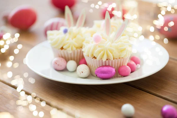 Magdalenas con huevos de Pascua y caramelos en la mesa — Foto de Stock