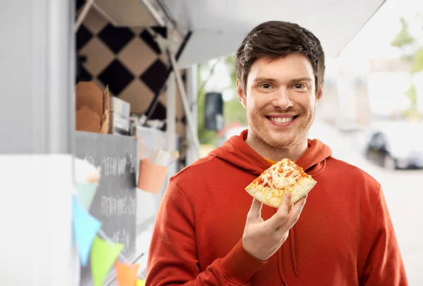 Jovem feliz comendo pizza no caminhão de comida — Fotografia de Stock