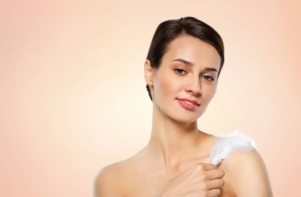 Beautiful woman with feather touching her shoulder — Stock Photo, Image