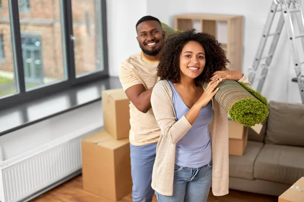 Glückliches Paar mit Teppich zieht in neues Zuhause — Stockfoto