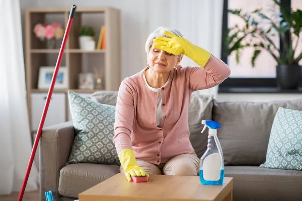 Cansado sênior mulher limpeza mesa em casa — Fotografia de Stock