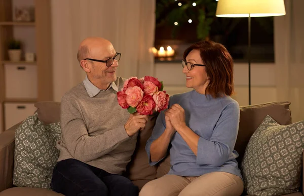 Gelukkig senior koppel met de bos bloemen thuis — Stockfoto