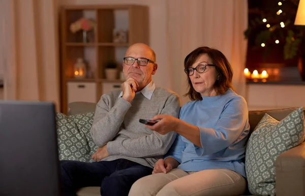 Idős pár néz TV-t otthon este Jogdíjmentes Stock Képek